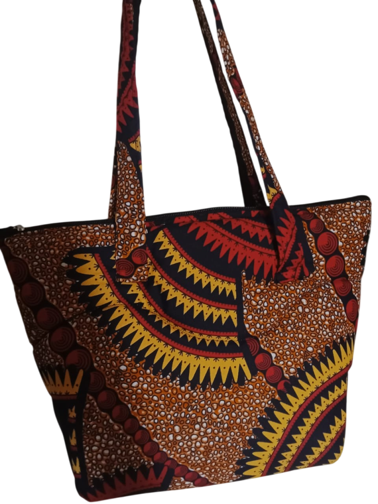 Upgrade your daily carry with our African Print Zip-Top Tote. Perfectly balancing functional design with high-impact aesthetics, this bag takes you from morning meetings to weekend brunch without missing a beat. Product Features: Secure Closure: Durable top zipper to keep your essentials safe. Spacious Design: Roomy interior for your laptop, makeup bag, and daily essentials. Sturdy Straps: Reinforced shoulder straps for comfortable all-day wear. Premium Fabric: 100% authentic African Wax Print (Ankara) with a structured lining.