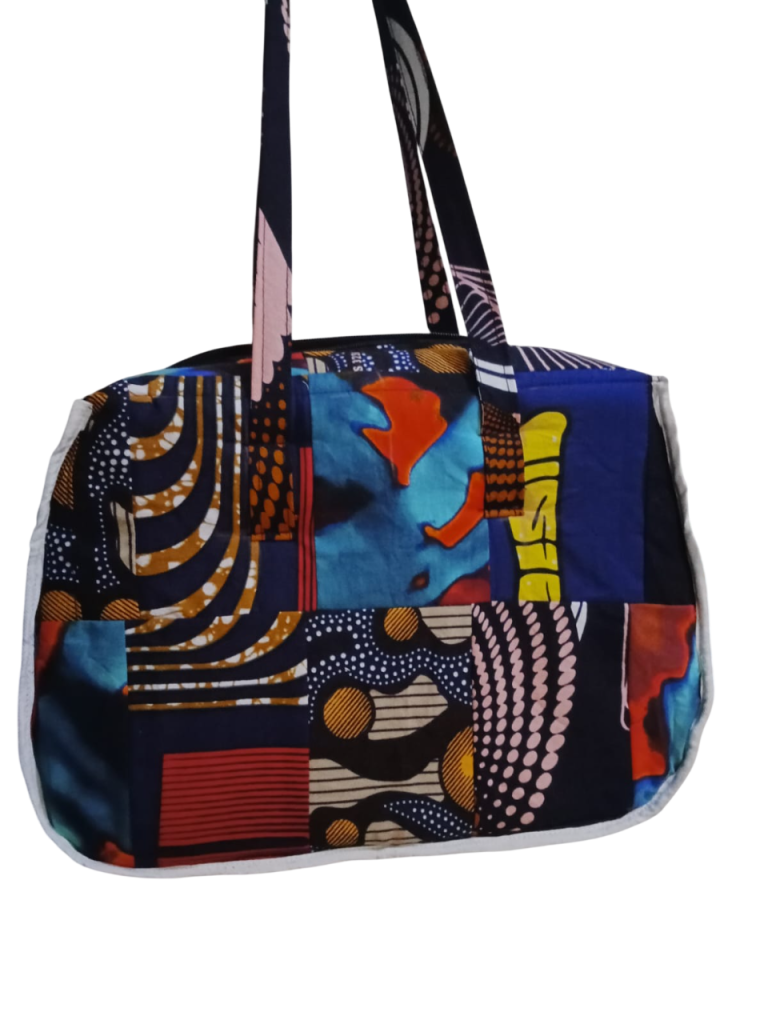 Upgrade your daily carry with our African Print Zip-Top Tote. Perfectly balancing functional design with high-impact aesthetics, this bag takes you from morning meetings to weekend brunch without missing a beat. Product Features: Secure Closure: Durable top zipper to keep your essentials safe. Spacious Design: Roomy interior for your laptop, makeup bag, and daily essentials. Sturdy Straps: Reinforced shoulder straps for comfortable all-day wear. Premium Fabric: 100% authentic African Wax Print (Ankara) with a structured lining.